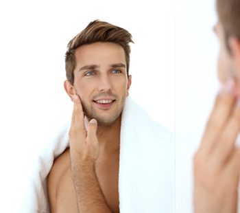 Man looking in mirror, admiring results of filler treatment