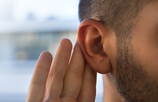 Man holding hand to ear, concerned about hearing loss