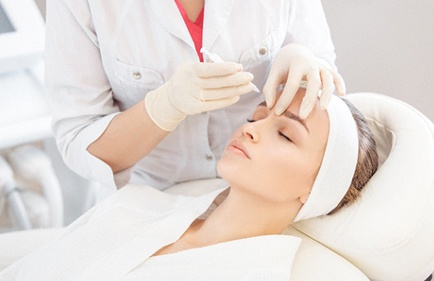 Woman relaxing while receiving BOTOX® injections between eyes
