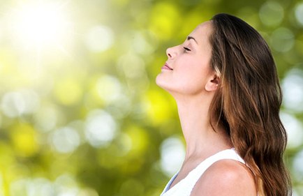 Woman standing outside, taking a deep breath