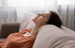 Woman leaning back on sofa, resting at home