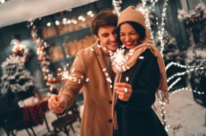 Couple smiling together while holding sparklers in holiday setting