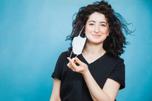 Woman removing mask after receiving cosmetic facial fillers