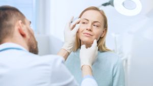 Doctor examining patient’s face during consultation