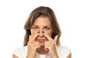 Young woman touching both sides of her nose 